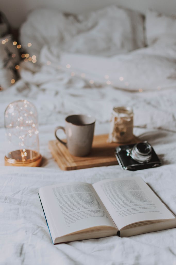 Cozy bedroom with coffee, book, and ambient string lights for relaxation.