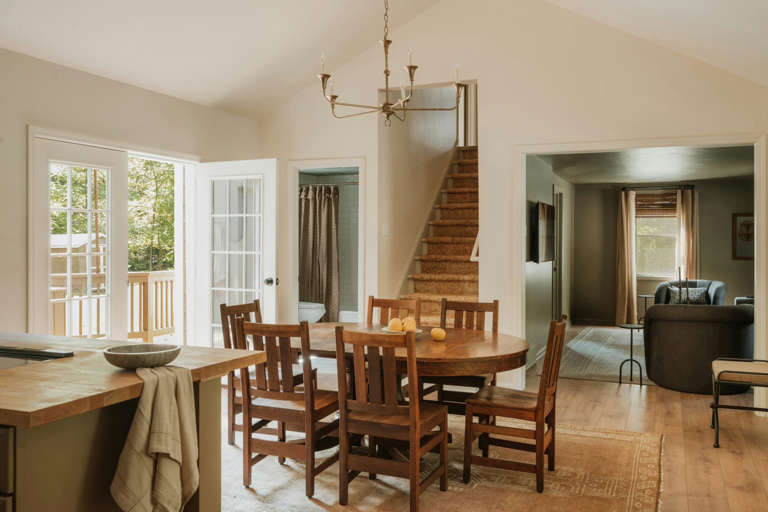 Salle à manger lumineuse style ferme avec table ovale et chaises en bois clair, ouverture sur la terrasse.